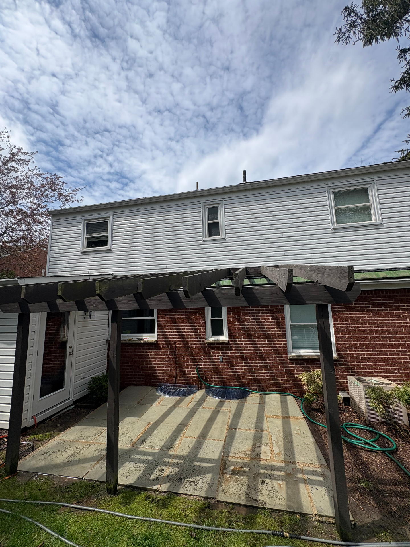 Same home after a full soft wash, with bright white siding, clean brick, and a restored flagstone patio.